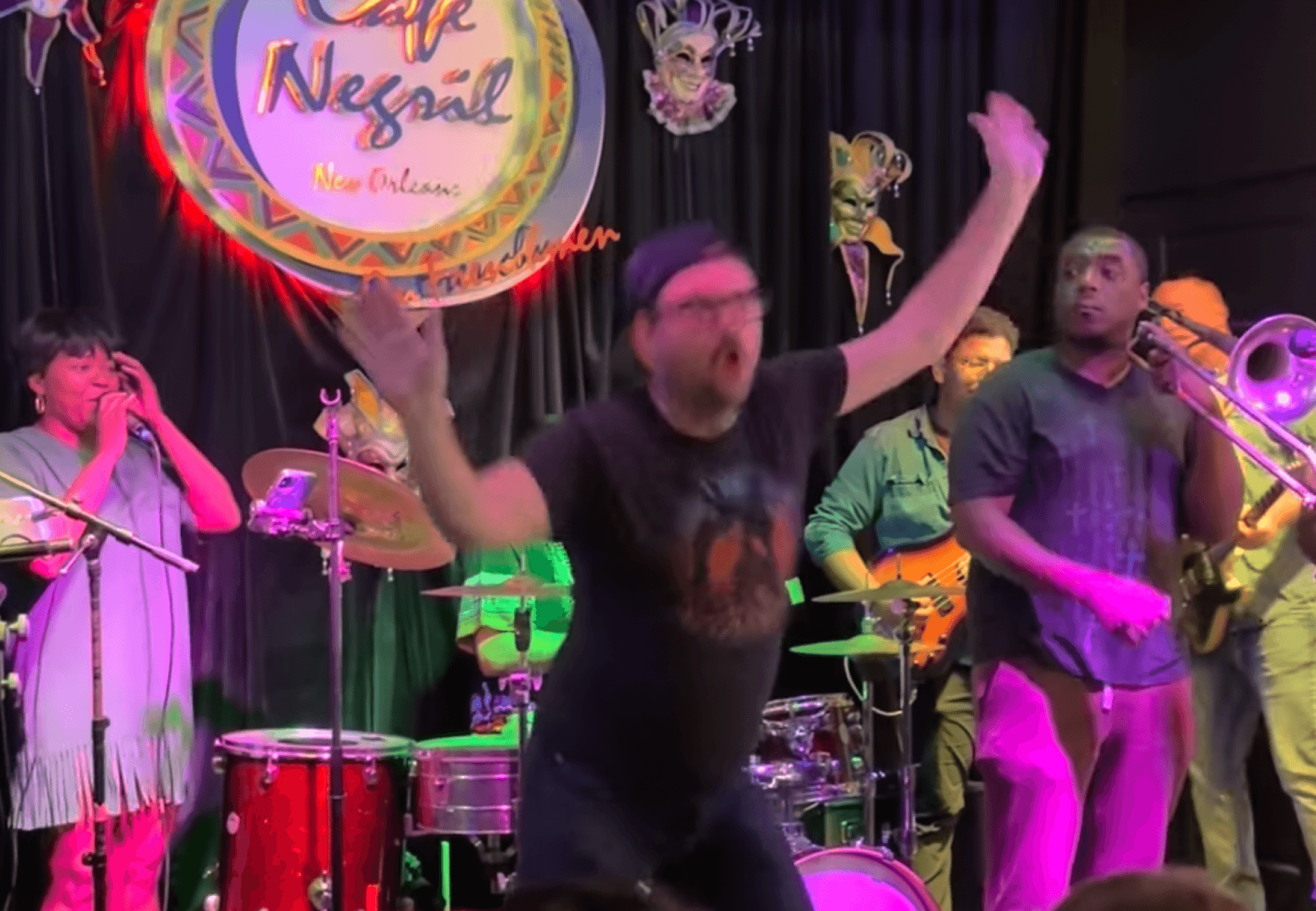 George dancing with one arm raised on stage with a band at Cafe Negril in New Orleans.